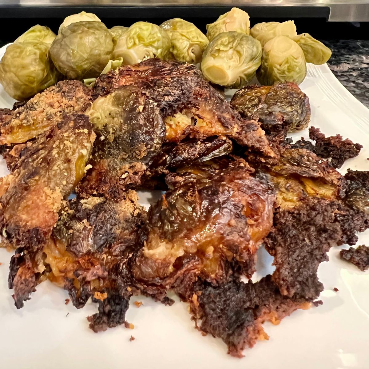Crispy mashed brussel sprouts on a plate with steamed brussel sprouts