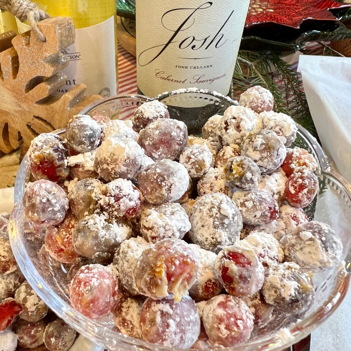 A bowl of frosted cranberries with 2 bottles of wine