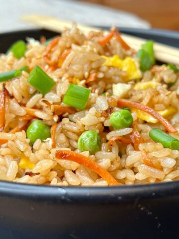 A bowl of healthy fried rice with peas carrots and scallions