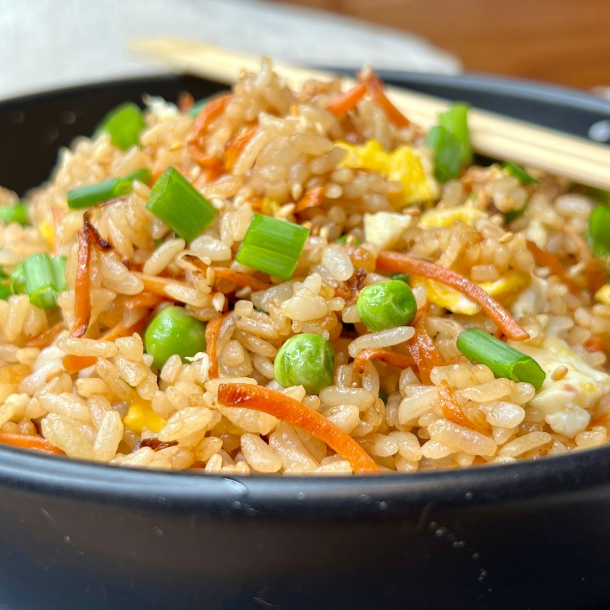 A bowl of healthy fried rice with peas carrots and scallions