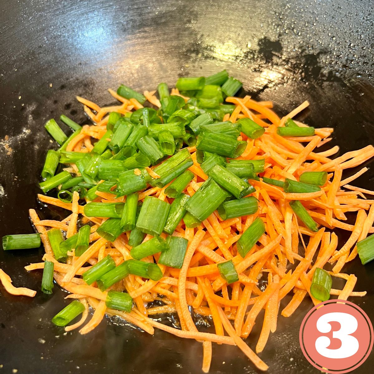 Shredded carrots and chopped scallions in a wok