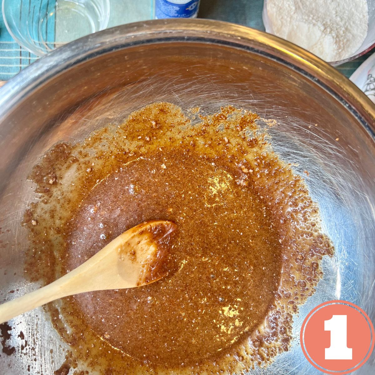 Chocolate Chip cookie batter with coconut sugar in a stainless steel mixing bowl with a wooden spoon