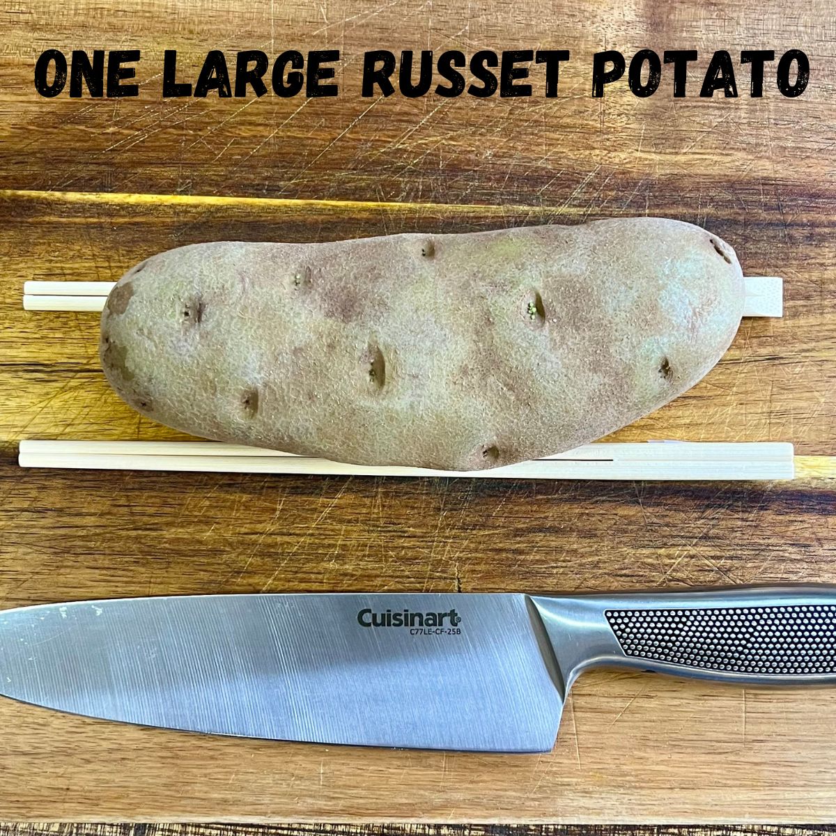 a russet potato with chopsticks and a stainless steel knife on a cutting board