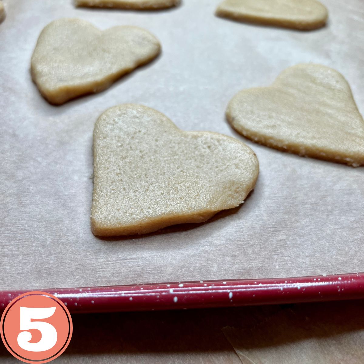 Heart shaped cookie dough on a baking sheet lined with parchment paper