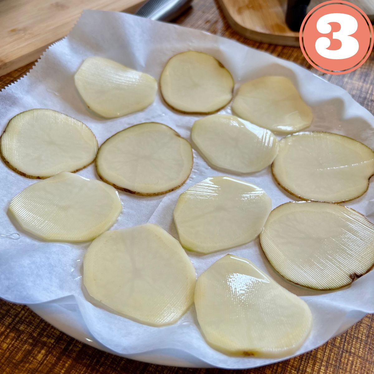 Sliced potatoes on parchment paper on a plate