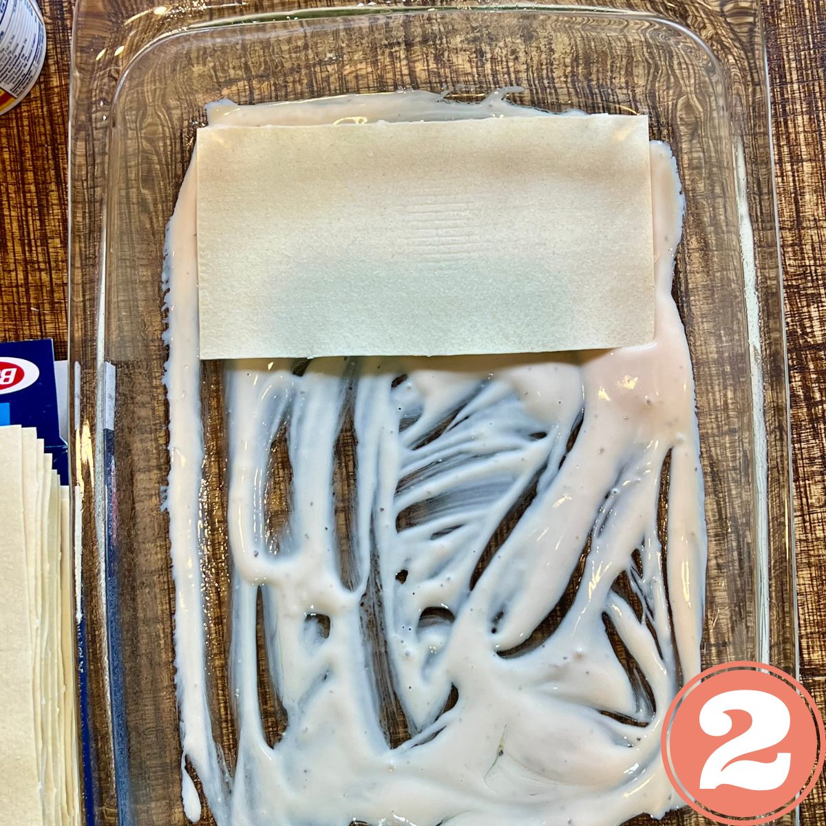 no bake lasagna noodle in a glass tray with Alfredo sauce