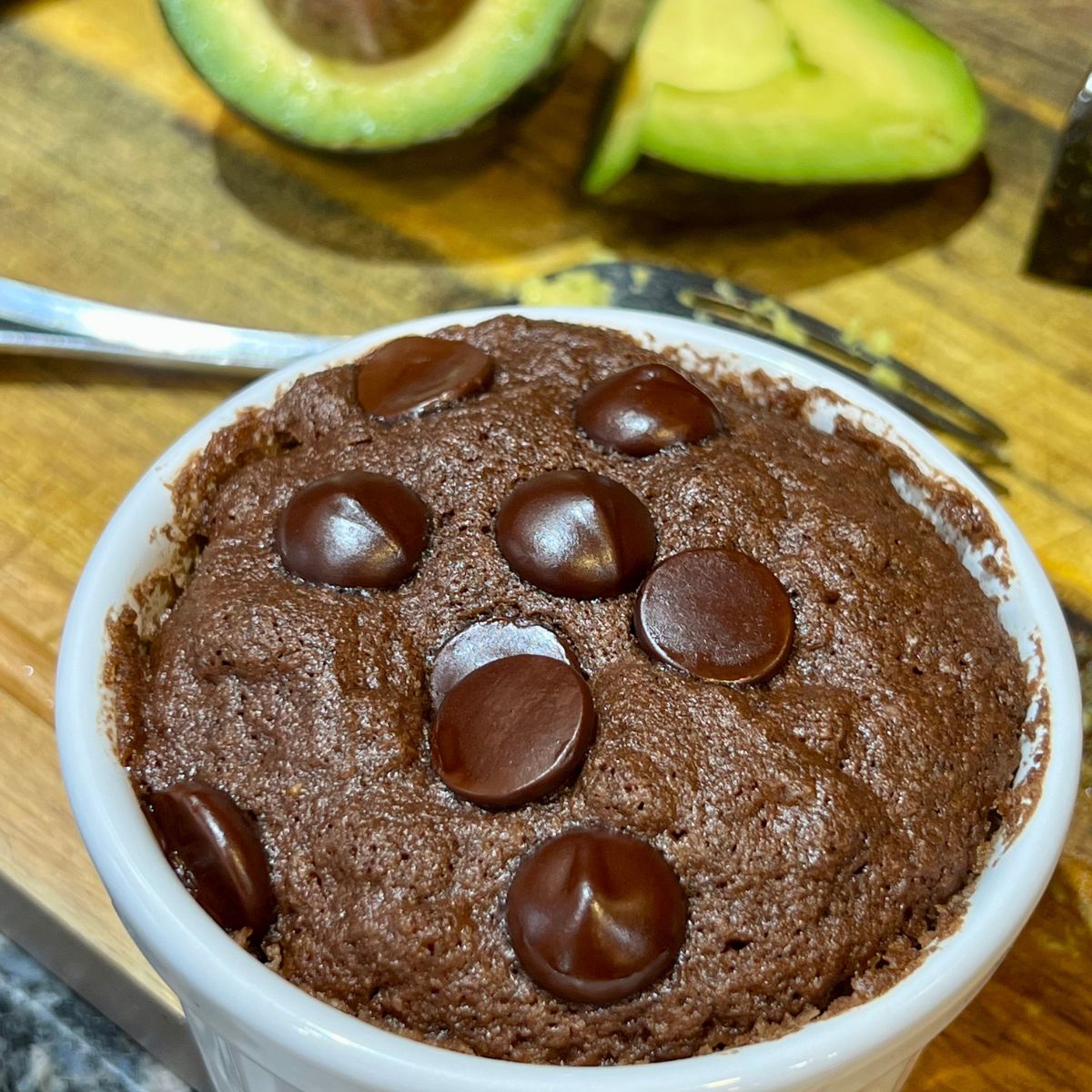 Chocolate avocado mug brownie in a white ramekin with sliced avocado