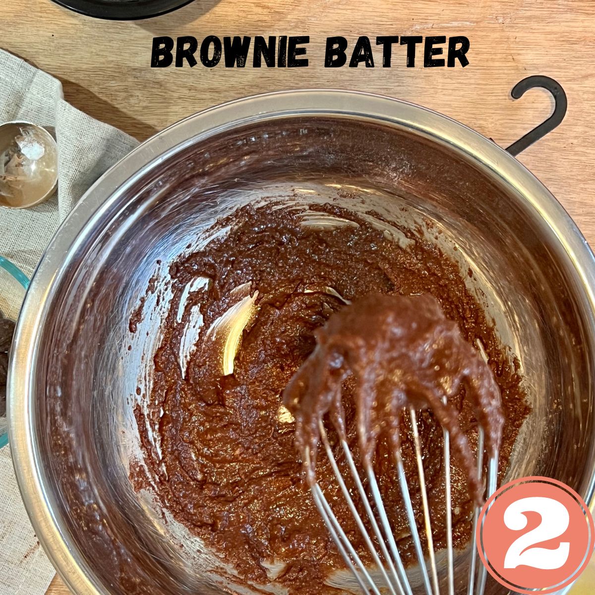 Chocolate mug brownie batter in a stainless steel bowl with a whisk in it