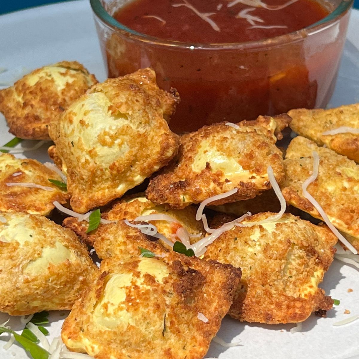 A plateful of air fried toasted raviolis with a side of marinara sauce