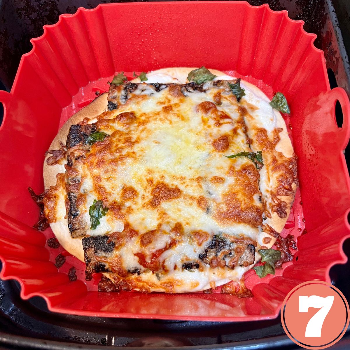 A crispy veggie air fryer pizza in a red silicone basket
