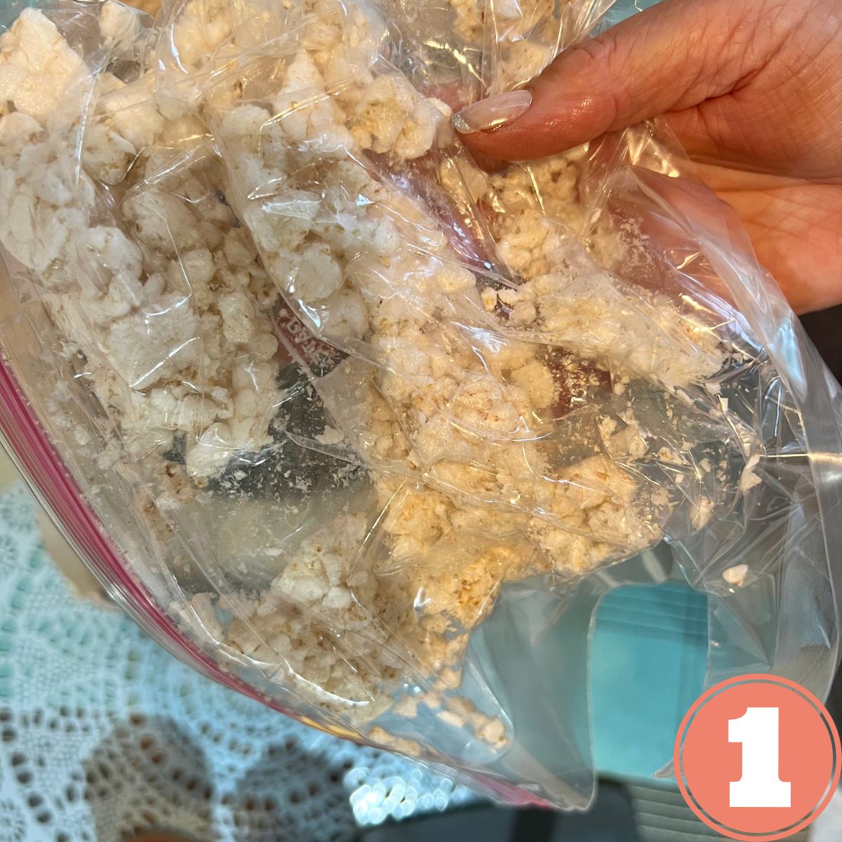 a hand holding a ziplock bag with a crumbled rice cake in it