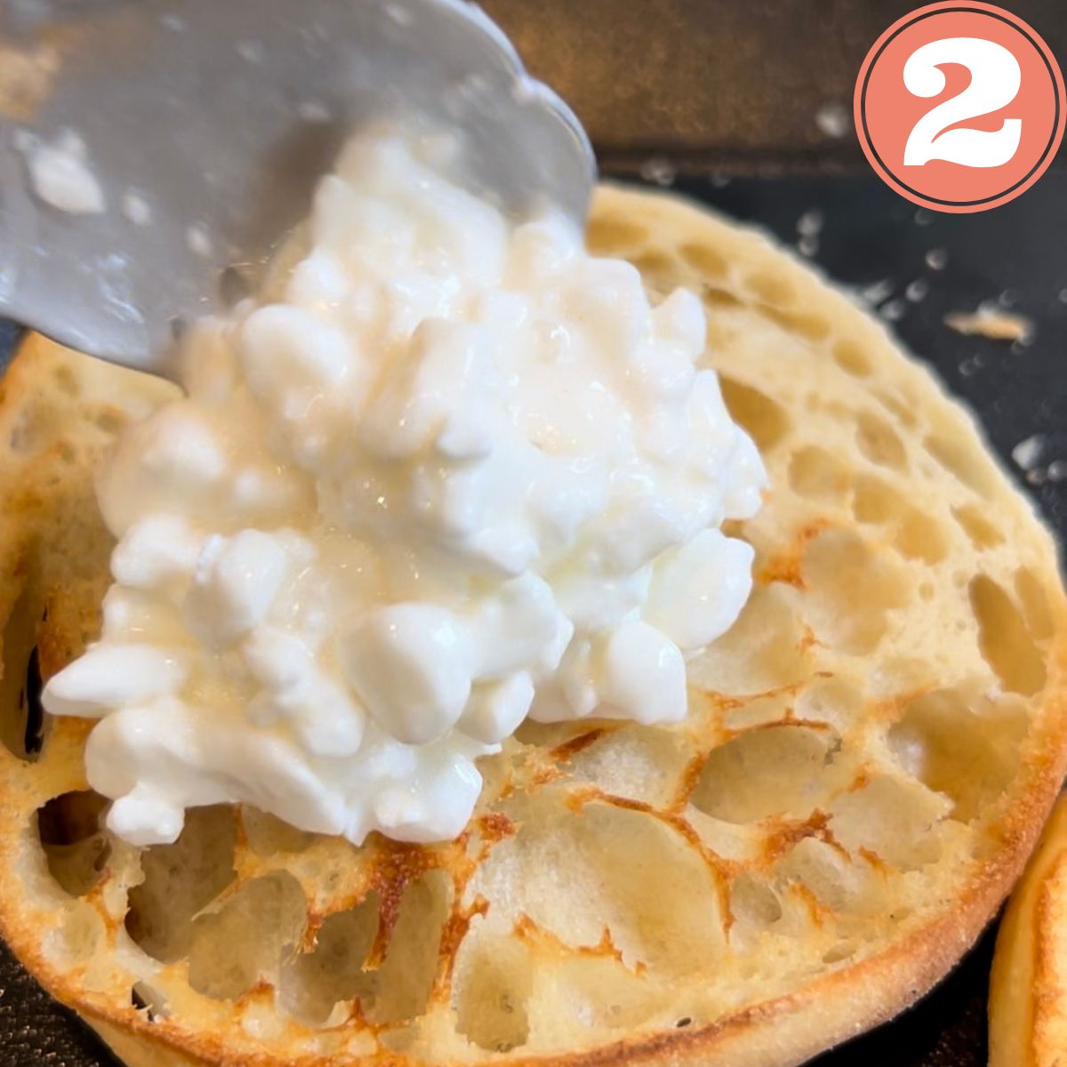 a spoon spreading cottage cheese on an English muffin