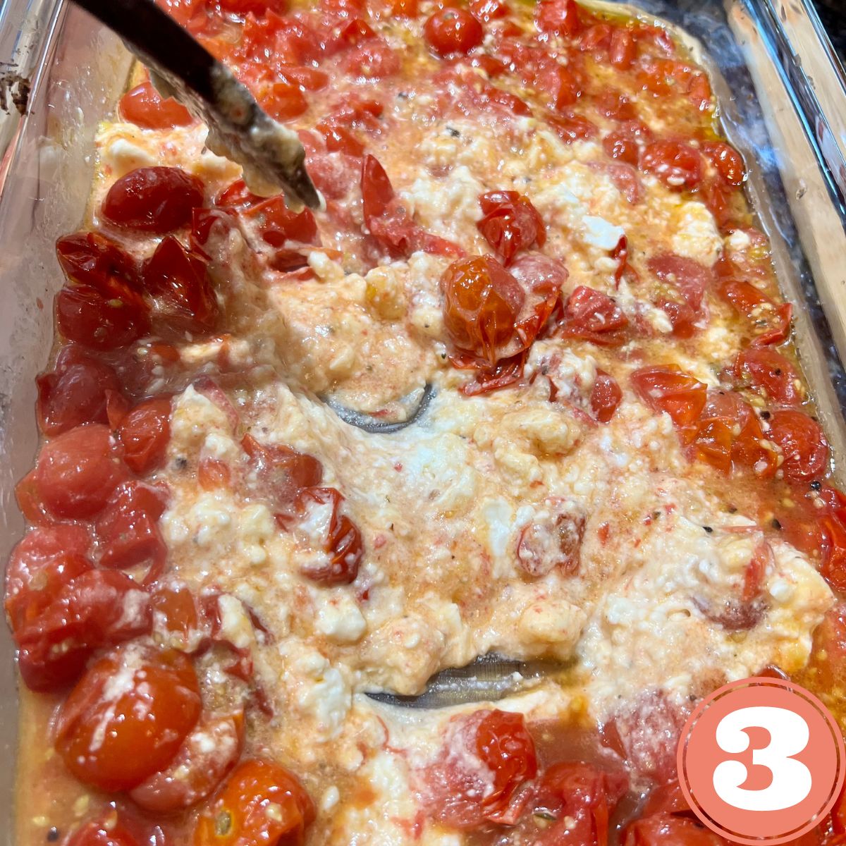 Cherry tomatoes and feta cheese being mixed together in a baking pan
