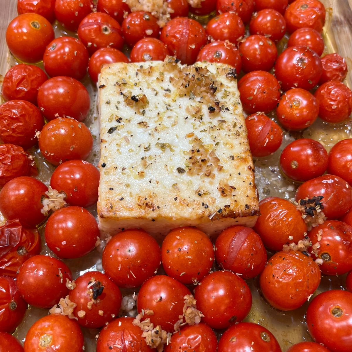Roasted cherry tomatoes with a block of feta cheese