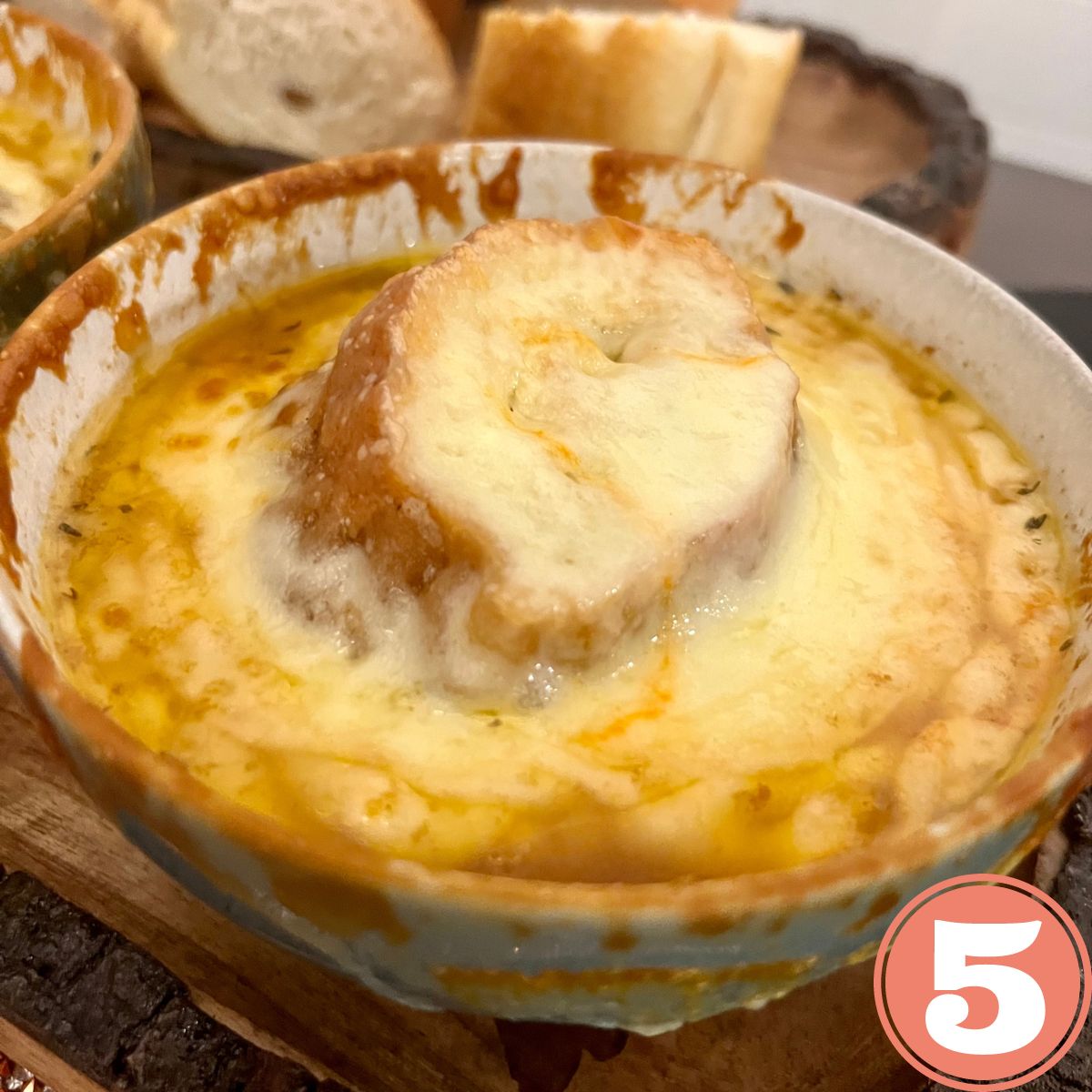 a bowl of authentic French onion soup with sliced Italian bread on the side