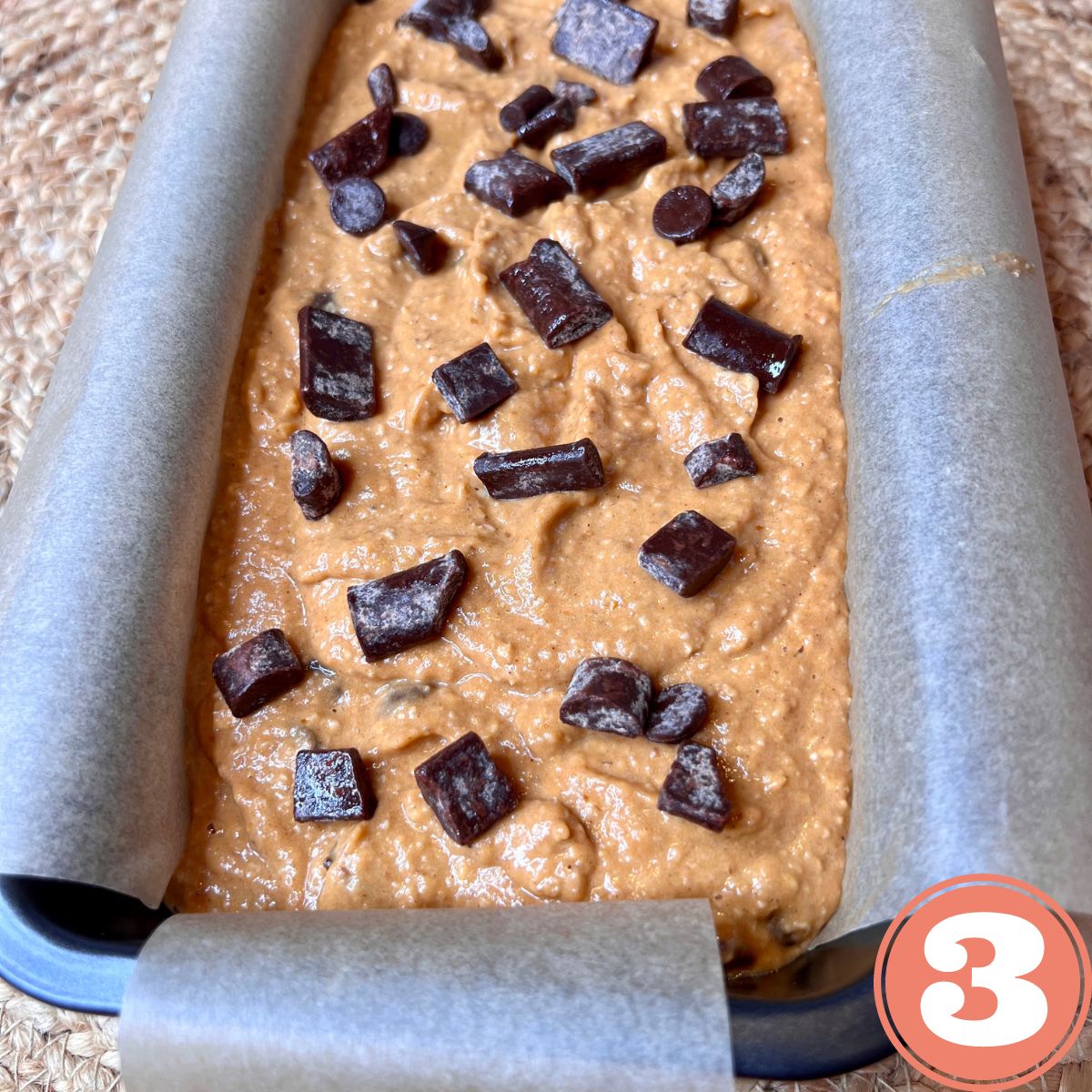 A loaf pan containing chocolate chip pumpkin loaf batter