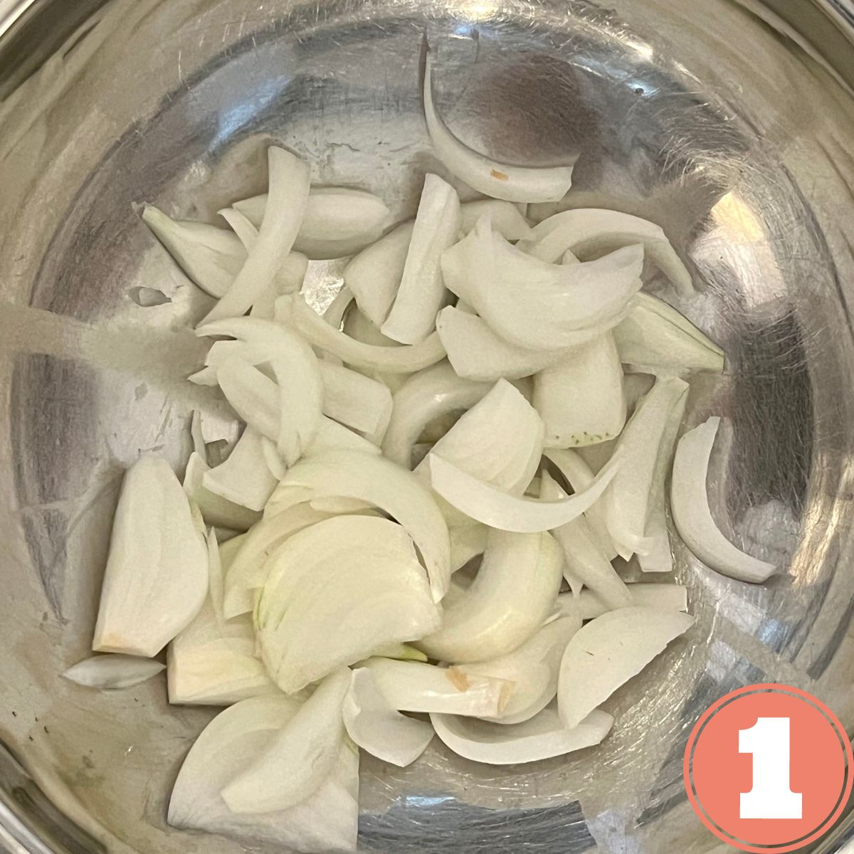 Sliced onions in a stainless steel bowl