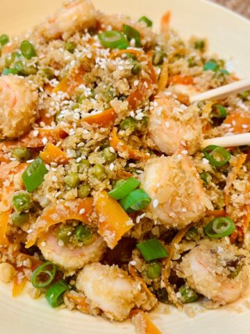 A bowl of cauliflower shrimp fried rice with chopsticks