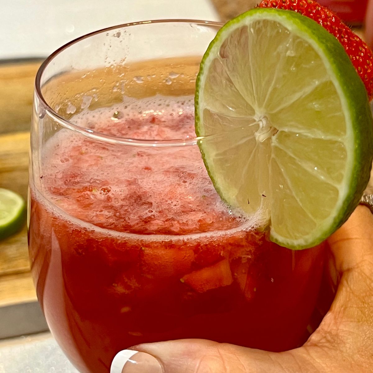 A hand holding a glass of a healthy berry mocktail