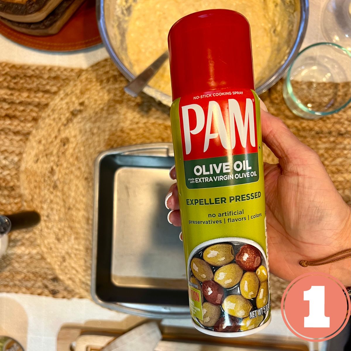 A hand holding a can of PAM spray olive oil