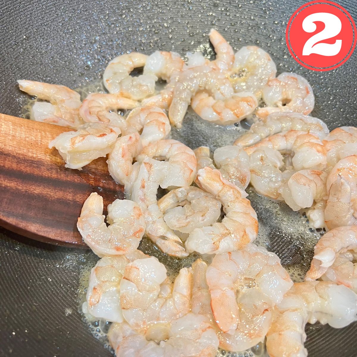 Shrimp in a wok with a wooden spoon