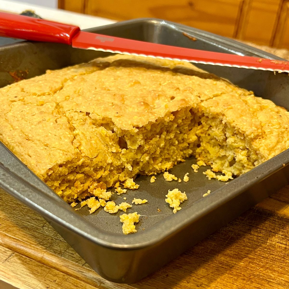 Sliced cornbread in a baking pan with a red knife