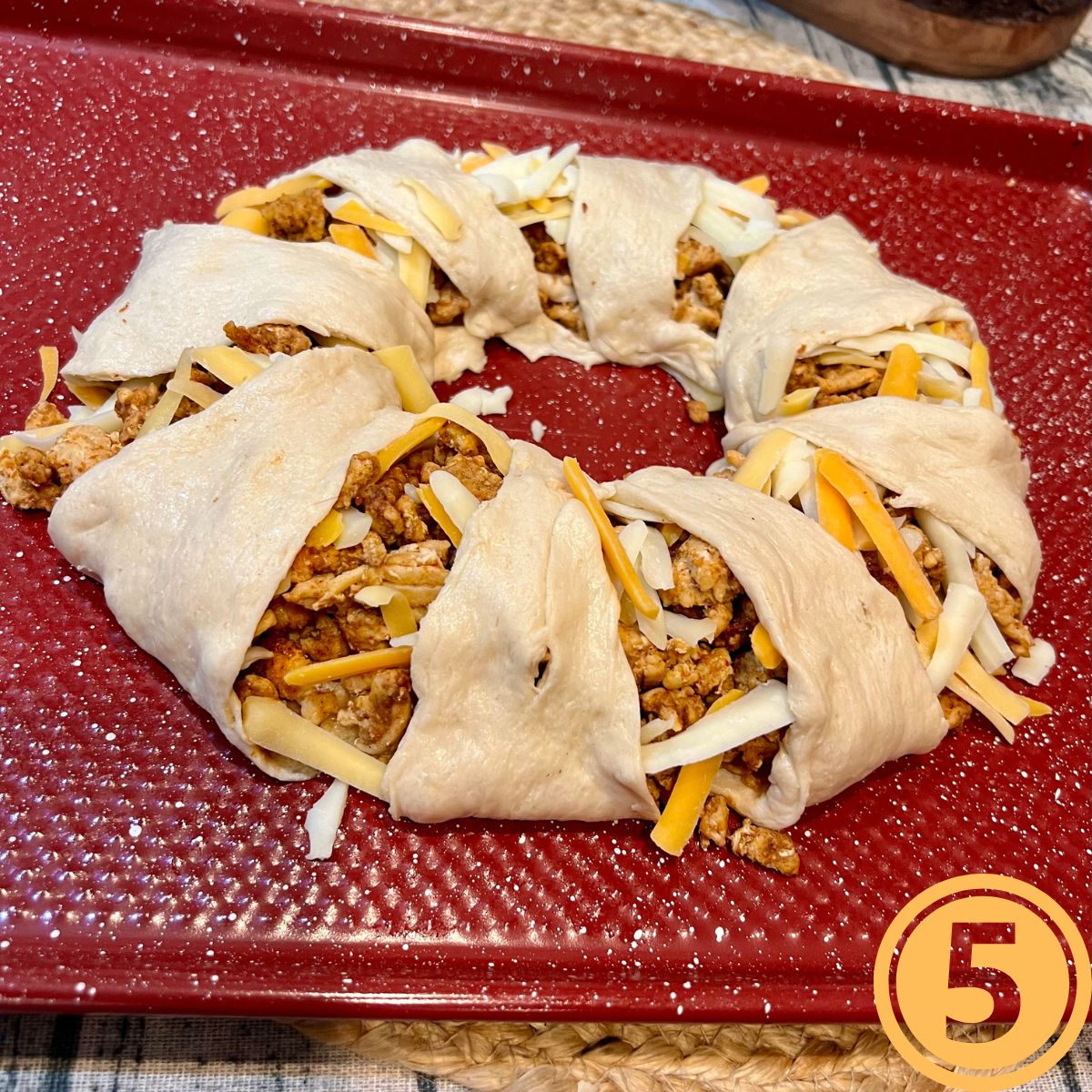 Crescent roll wrapped taco ring on a red pan