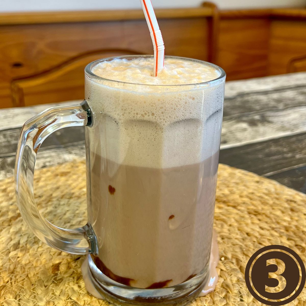 Foamy WW Chocolate Egg Cream in a glass with a straw on a table