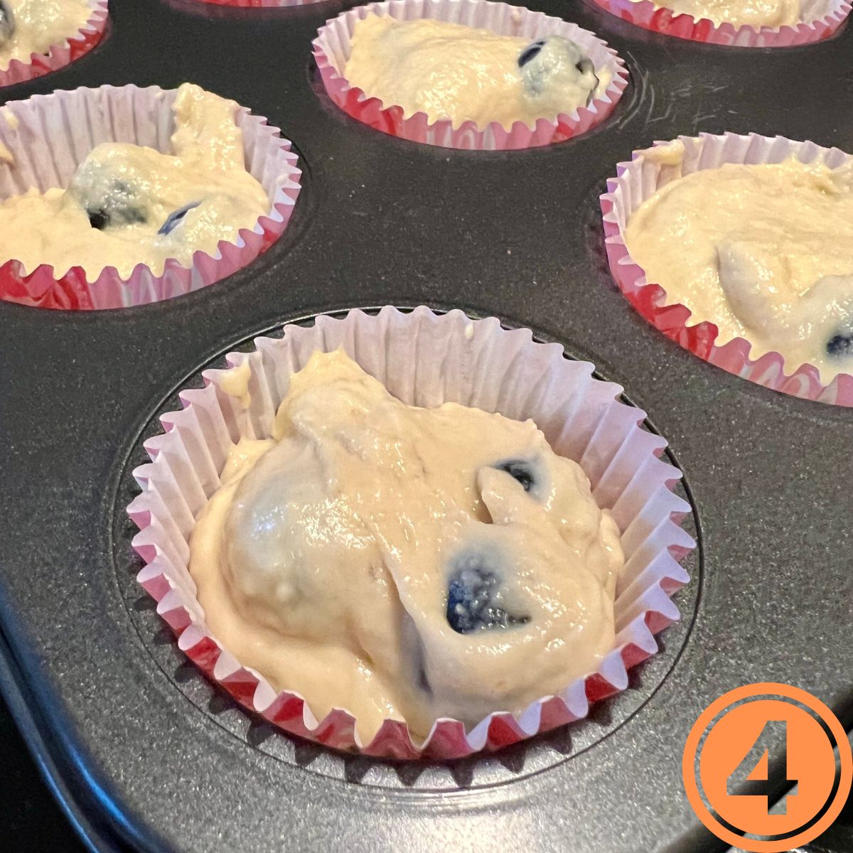 Banana Blueberry muffin batter in a muffin tin in paper liners