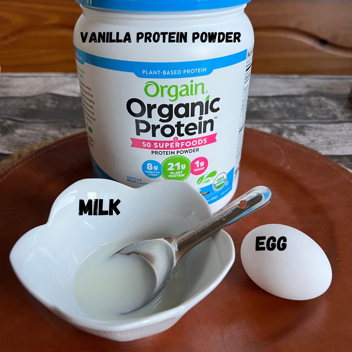 A jug of protein powder, one egg and a bowl of milk 