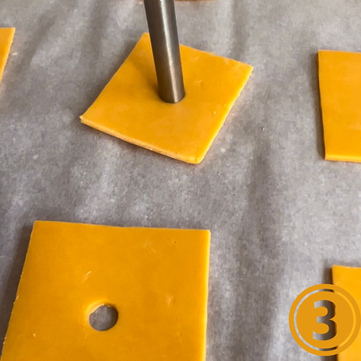 A metal straw making holes in the center of cheese slices