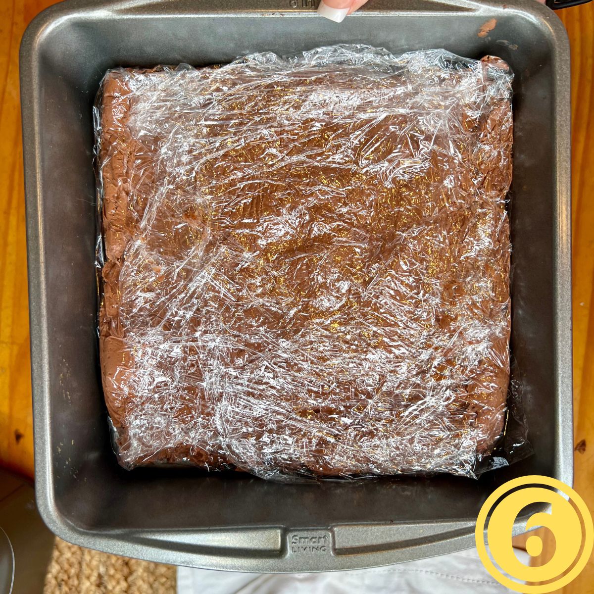 Chocolate fudge wrapped in plastic wrap in a baking pan
