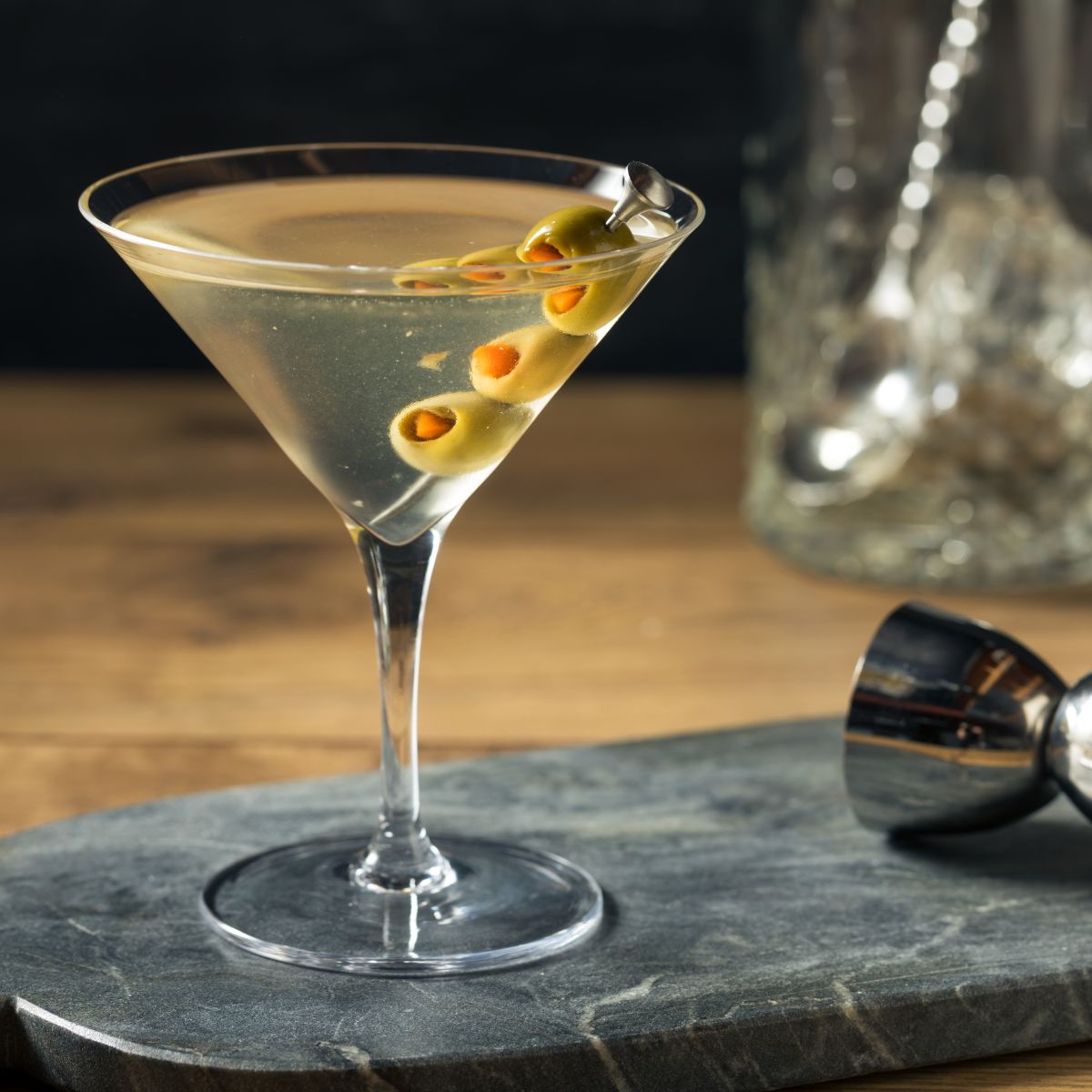 A martini with olives on a bar