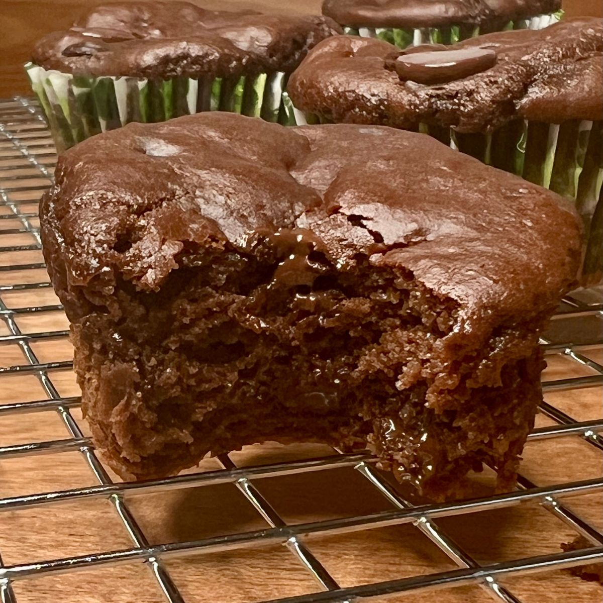 Chocolate chip protein muffin on a wire rack with a bite taken out of it