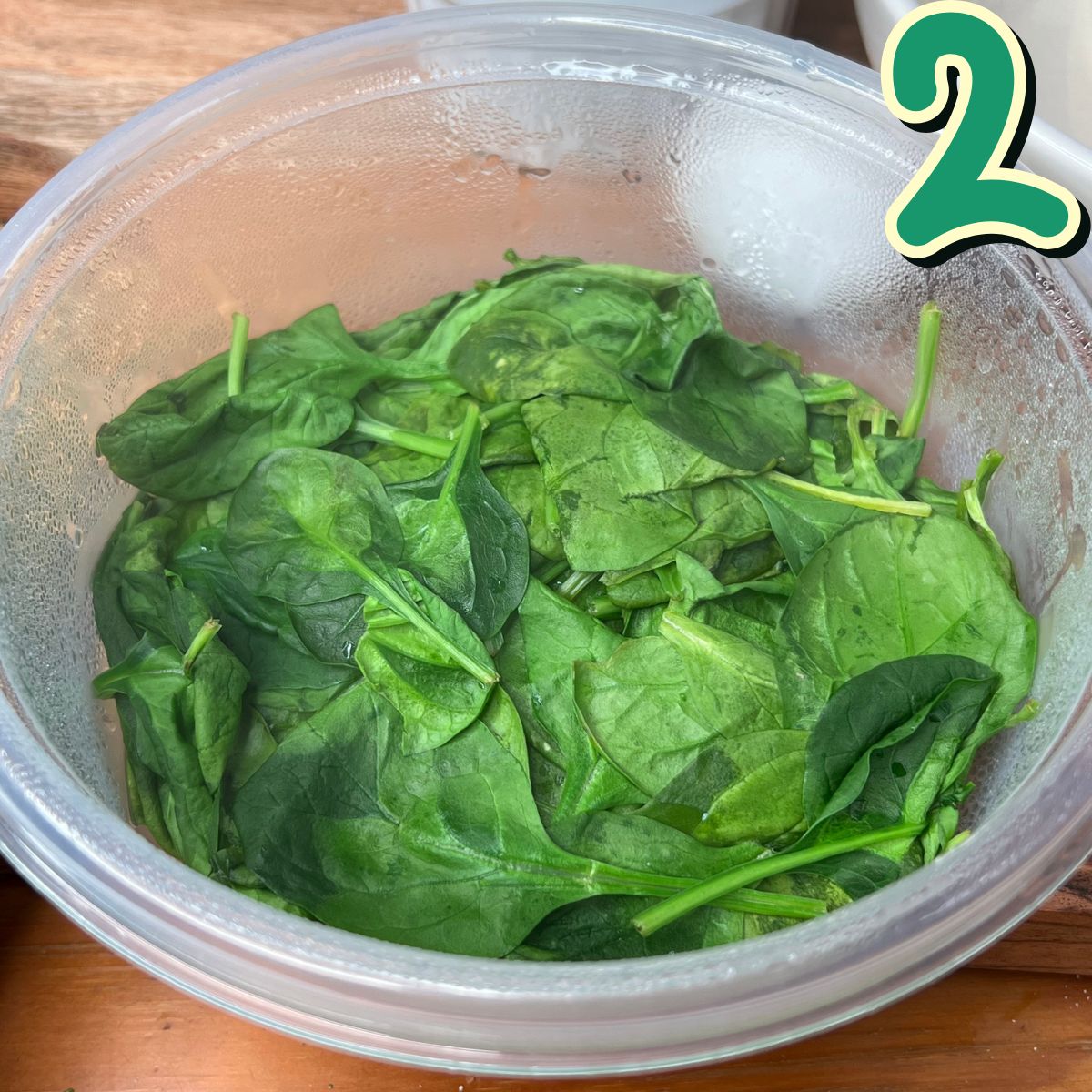 Steamed spinach in a clear Tupperware bowl