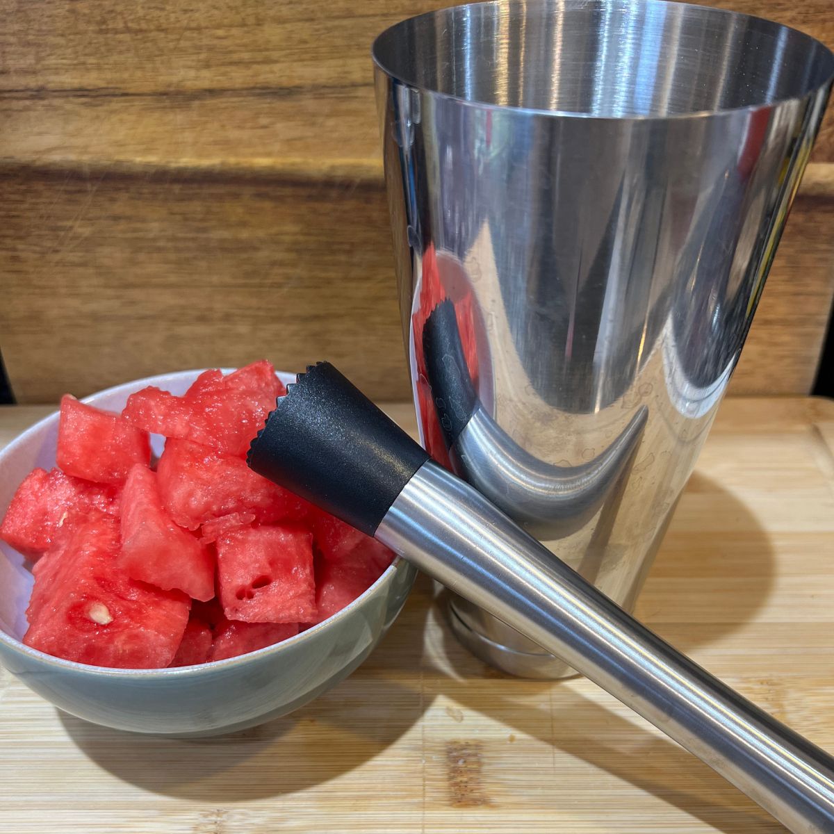 Watermelon in a bowl with a stainless steel muddler