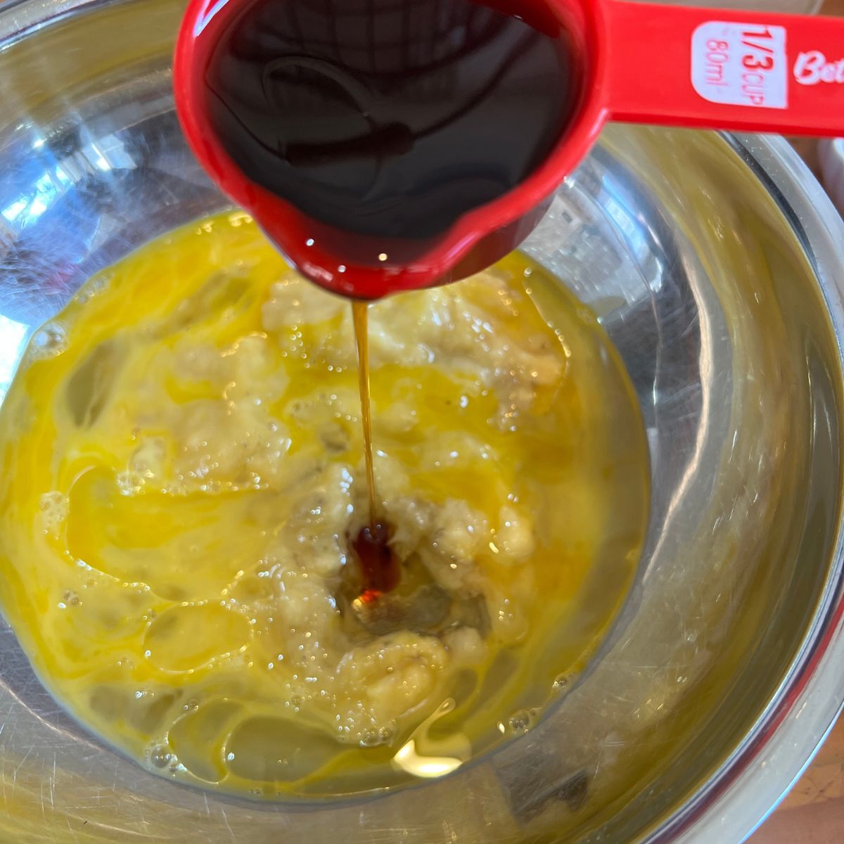 Pouring maple syrup into churro muffin batter