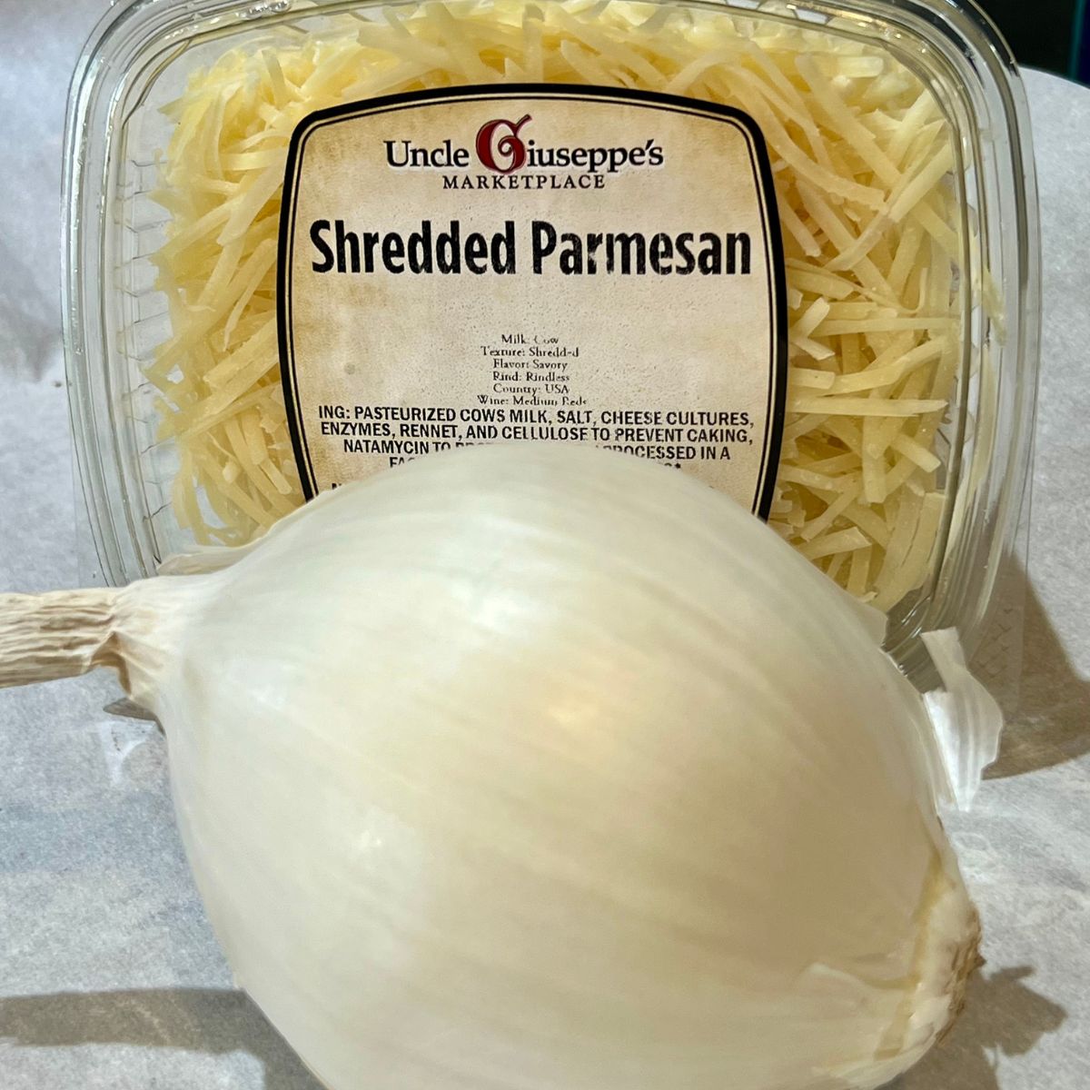 a white onion and a box of shredded parmesan cheese