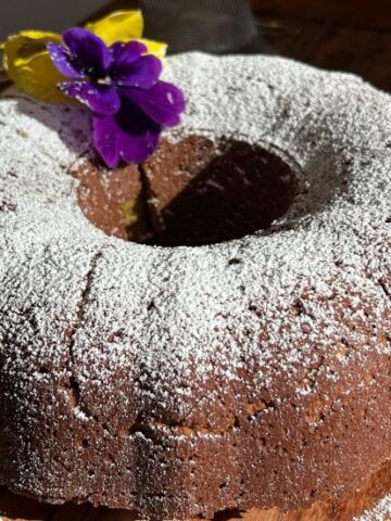 Avocado cake covered with powdered sugar and a purple pansy flower
