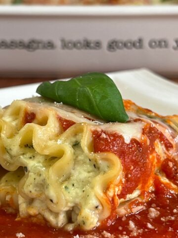 Cottage cheese lasagna roll-up on a plate with basil