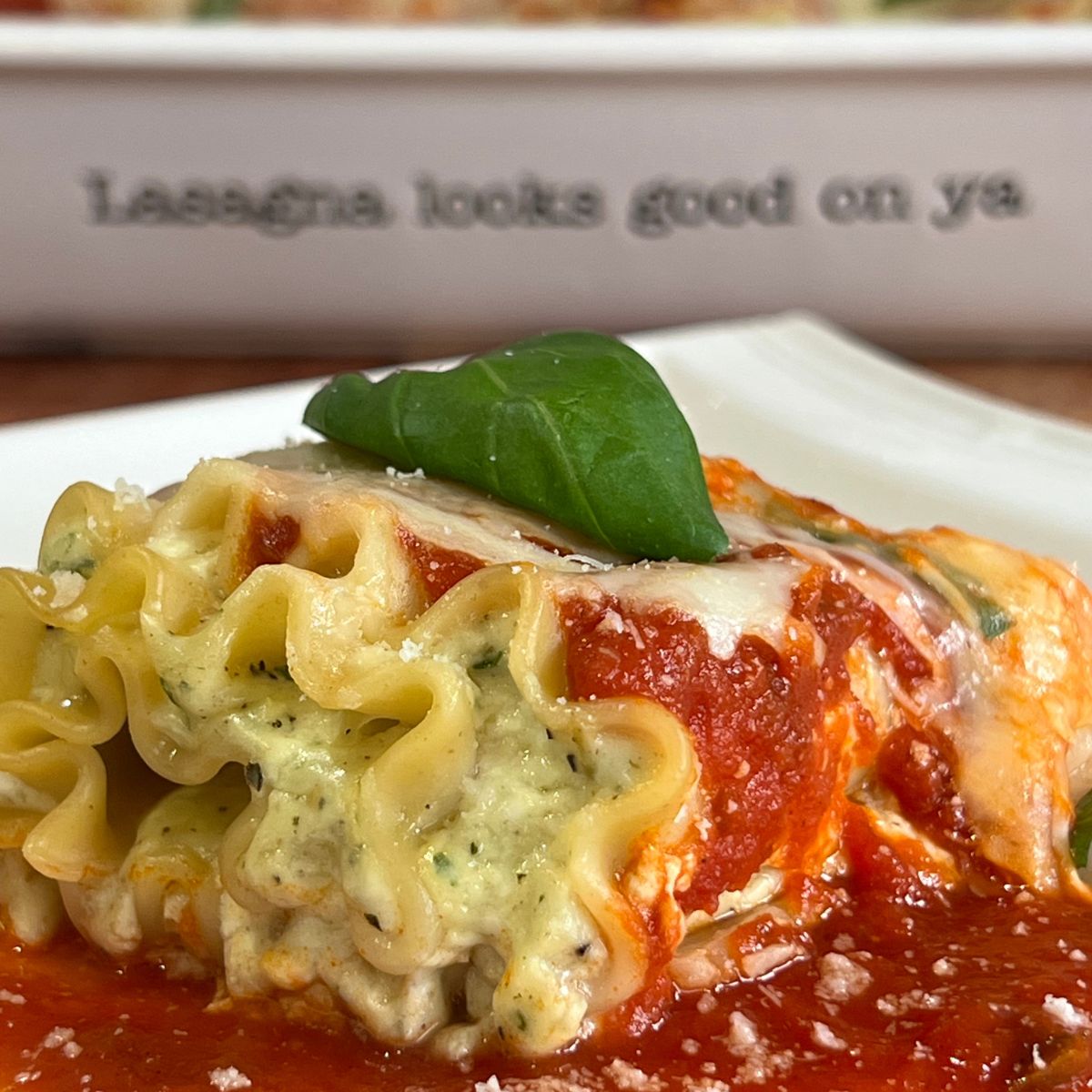 Cottage cheese lasagna roll-up on a plate with basil