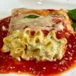 Lasagna roll-up filled with cottage cheese and Greek yogurt and pesto on a plate with marinara sauce