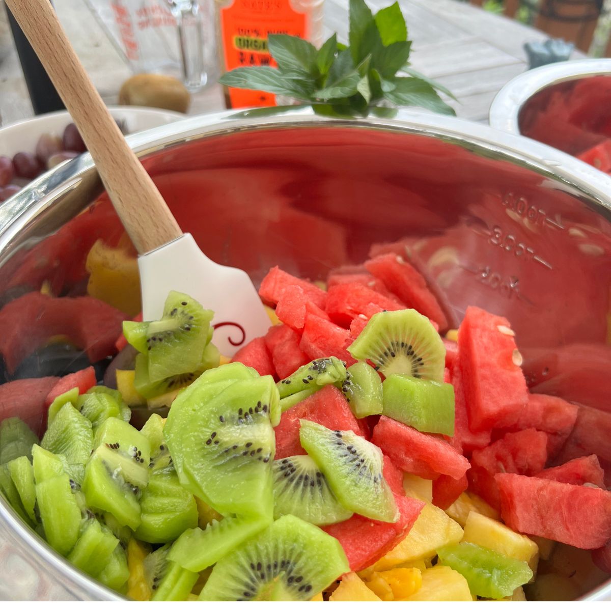 Sliced kiwi, watermelon, pineapple, mango and grapes in a bowl for lime zest fruit salad