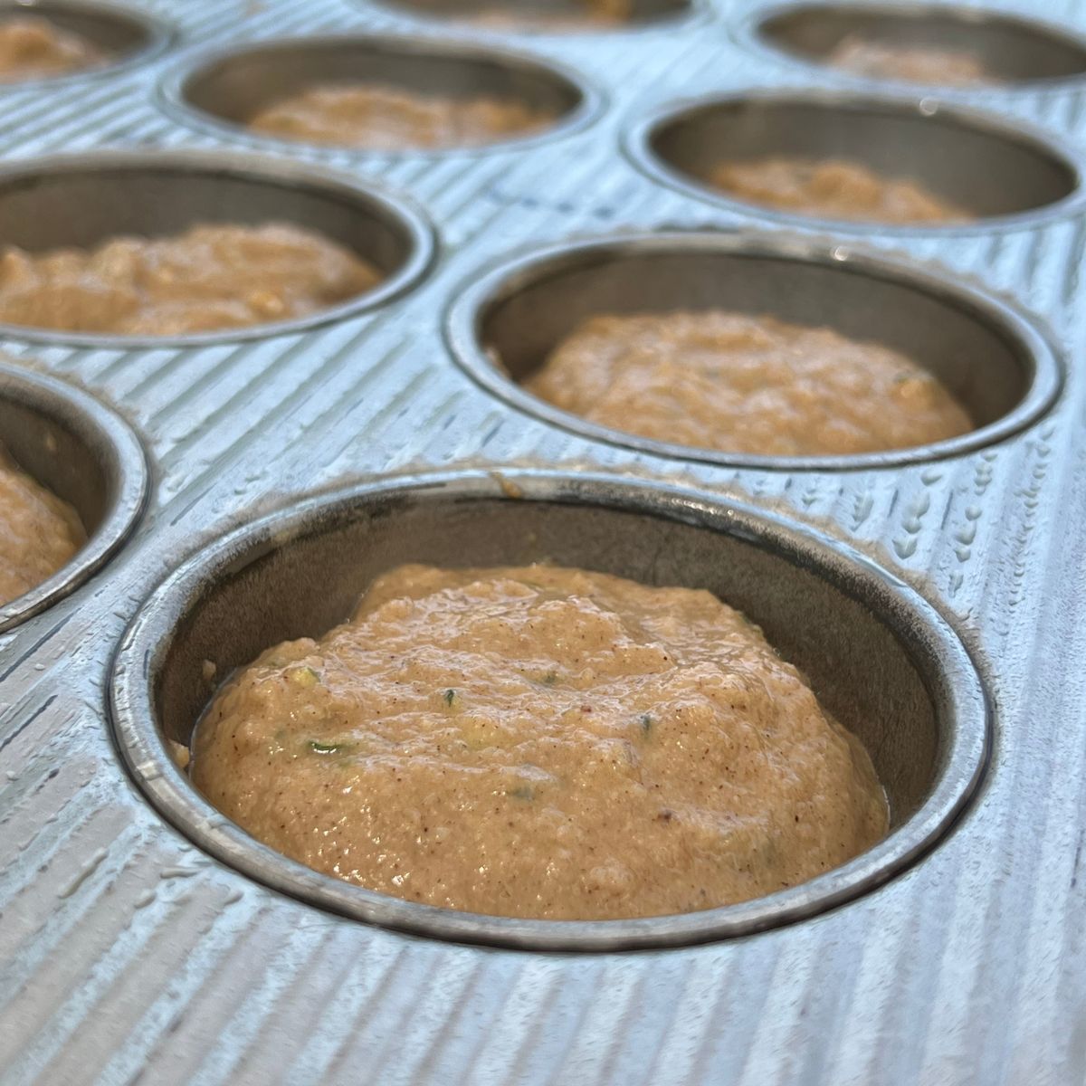 Healthy zucchini muffin batter in a muffin pan
