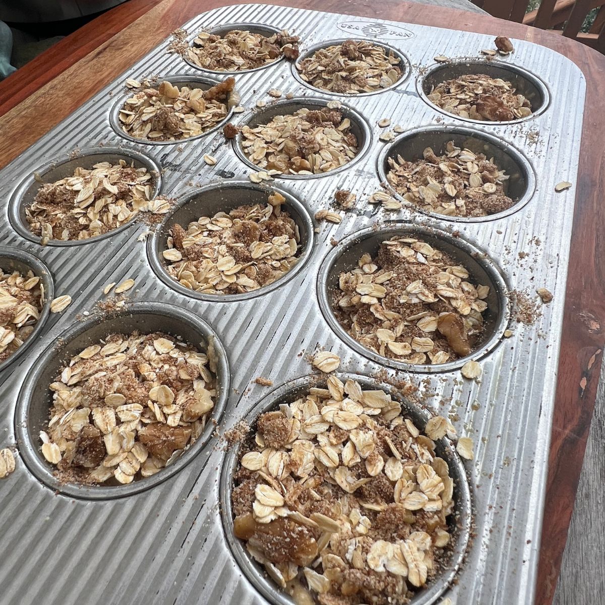 Crumble topped banana zucchini muffin batter in a muffin tin