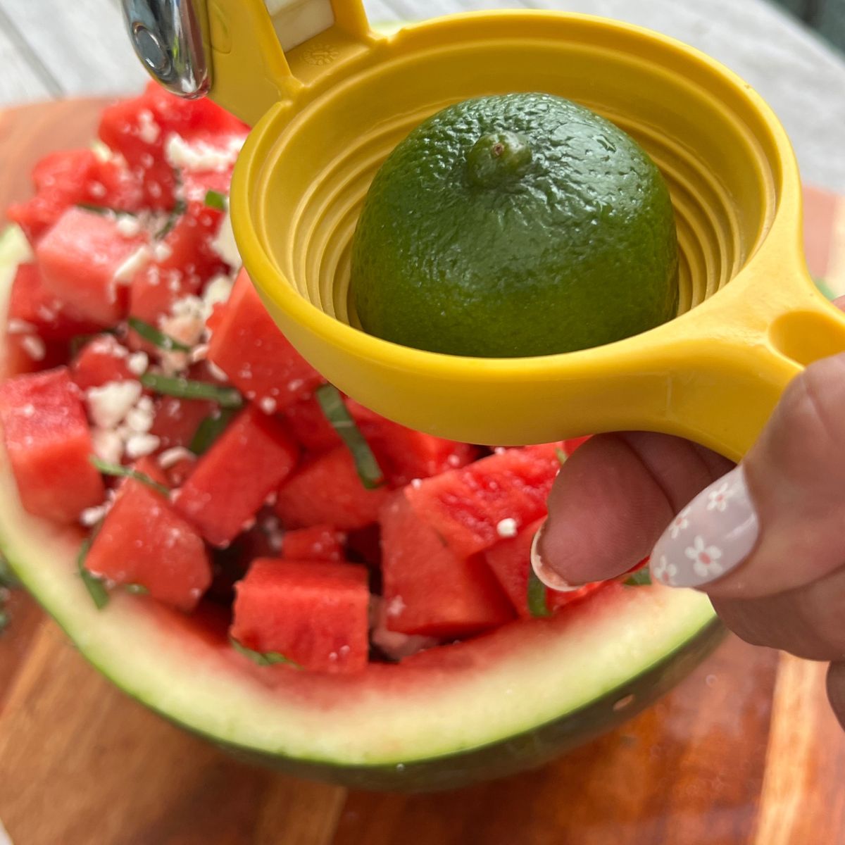 Squeezing fresh lime juice over a watermelon feta cheese salad