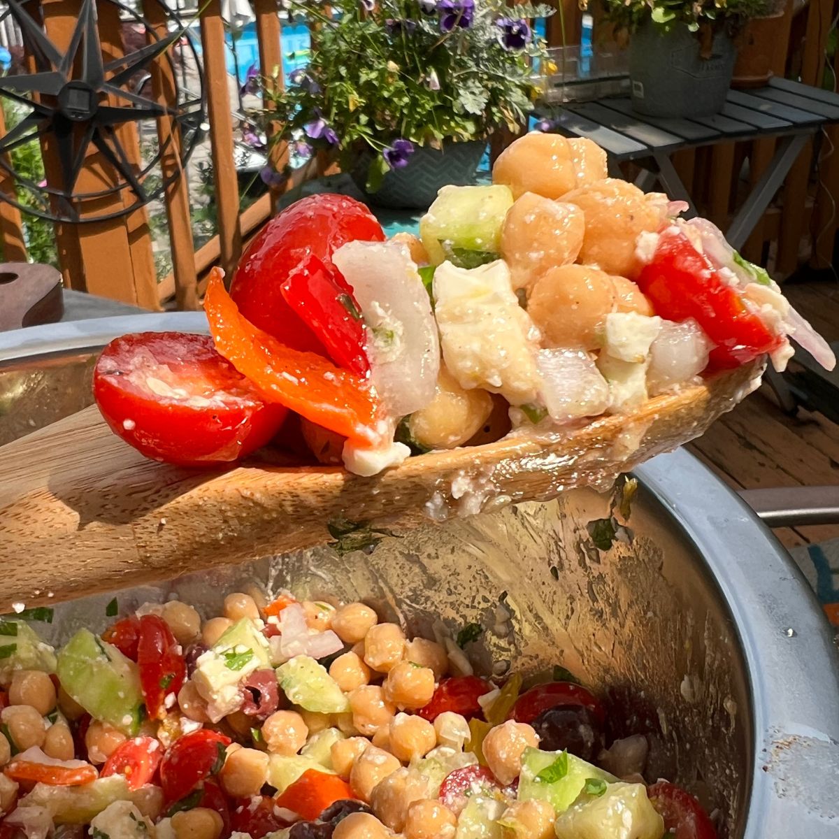 Summer chickpea salad with lemon feta dressing on a wooden spoon