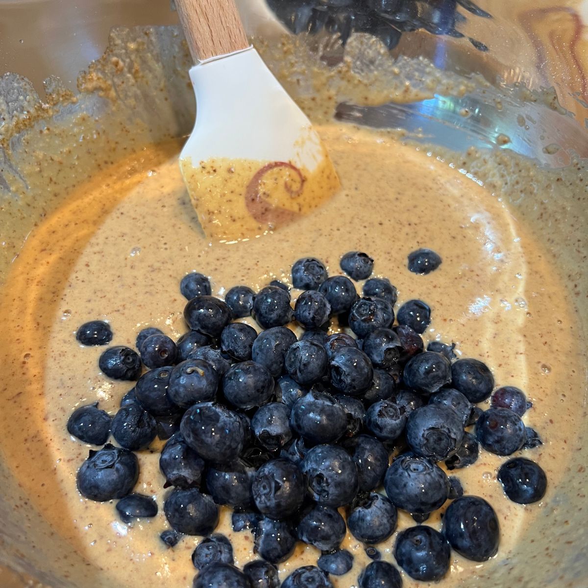 A spatula folding blueberries in to die for muffin batter