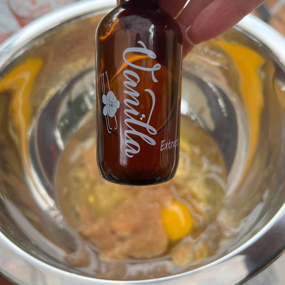 Vanilla extract over a bowl of zucchini banana muffin ingredients
