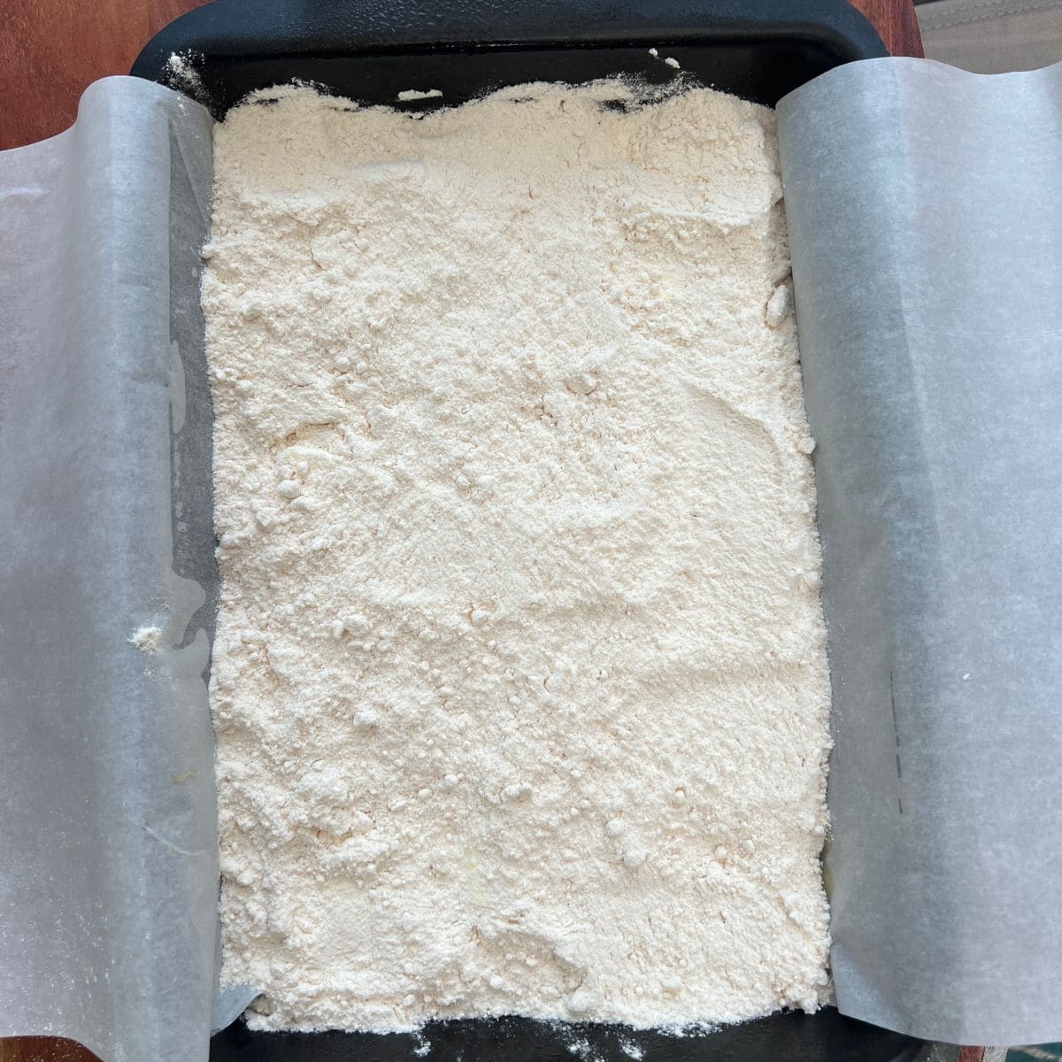 Dry cake mix sprinkled in a baking pan for a dump cake recipe